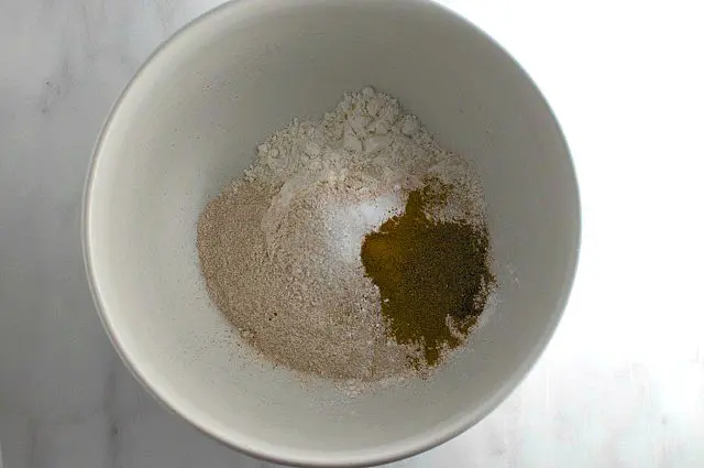 Looking down on a white bowl with flour and spices.