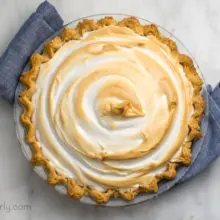 Looking down on a pie sitting on a blue kitchen towel. The meringue has golden edges.