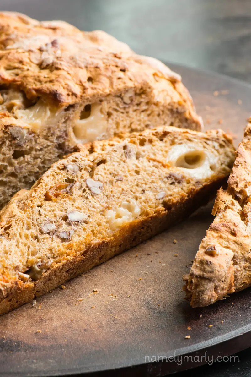 A slice of fig and pecan rustic loaf sits next to the rest of the loaf.