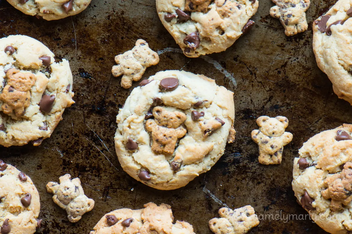 Looking down on teddy graham chocolate chip cookies on a baking dish with more teddy graham cookies beside them.
