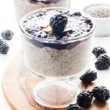 Vegan Banana Chia Pudding with Blackberry Sauce in a serving dish with another dish behind it and fresh blackberries around it.