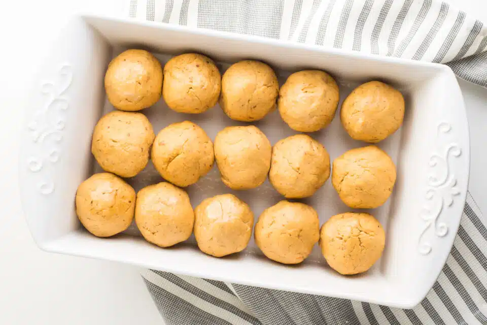 Several dinner rolls in a baking dish waiting to rise before baking.
