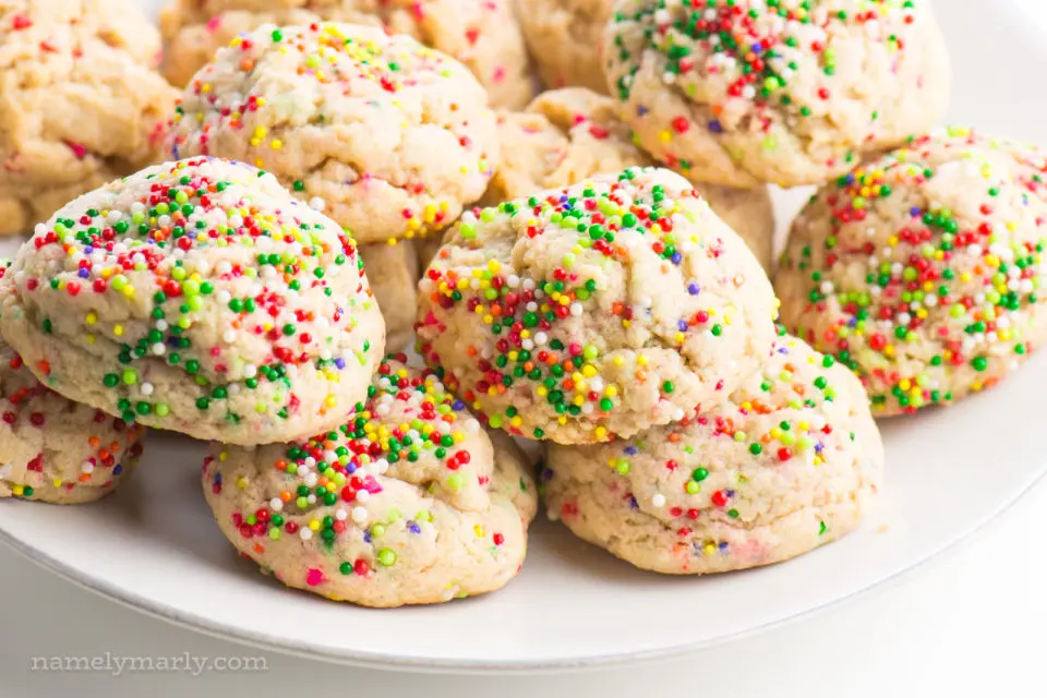A white plate is full of confetti cookies, with colorful sprinkles.
