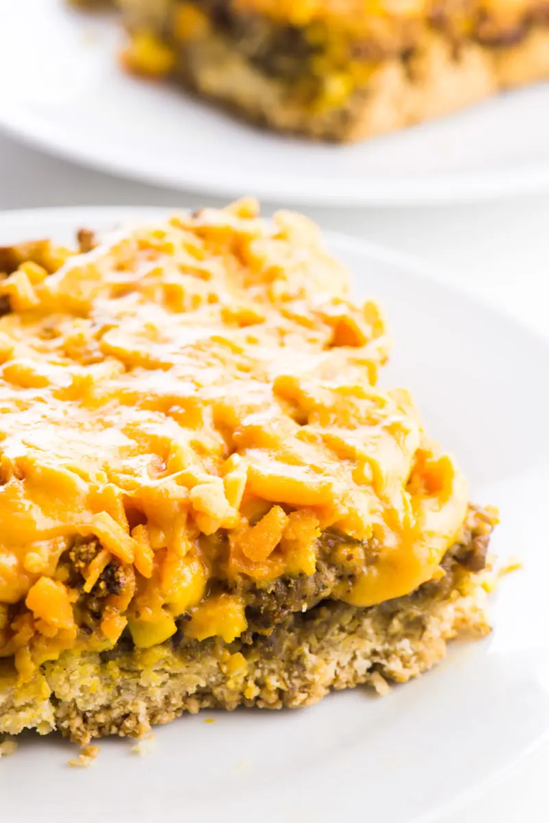 A slice of vegan breakfast casserole sits on a plate with another slice behind it.