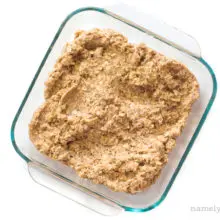 The batter for oatmeal bars has been pressed into the bottom of a square baking pan.