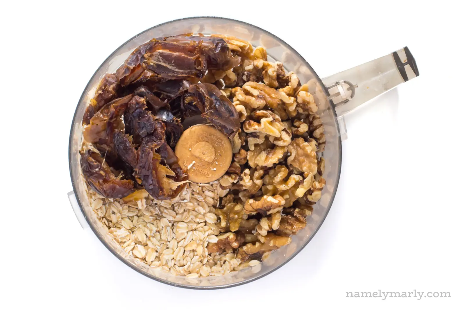 Oatmeal, dates, and walnuts in a food processor bowl.