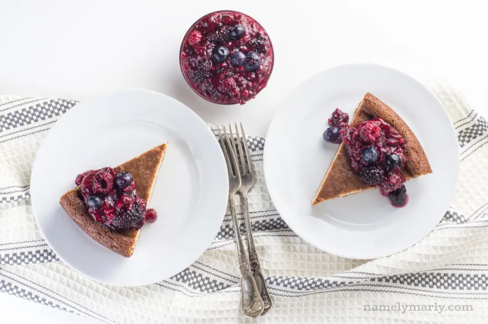 Looking down on plated slices of dairy free cheesecake with berry filling in a bowl between them.