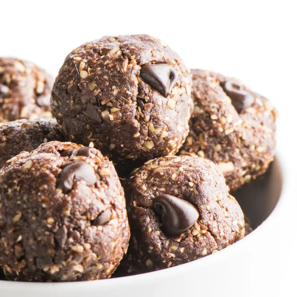 A close-up of chocolate no bake energy balls in a white bowl.