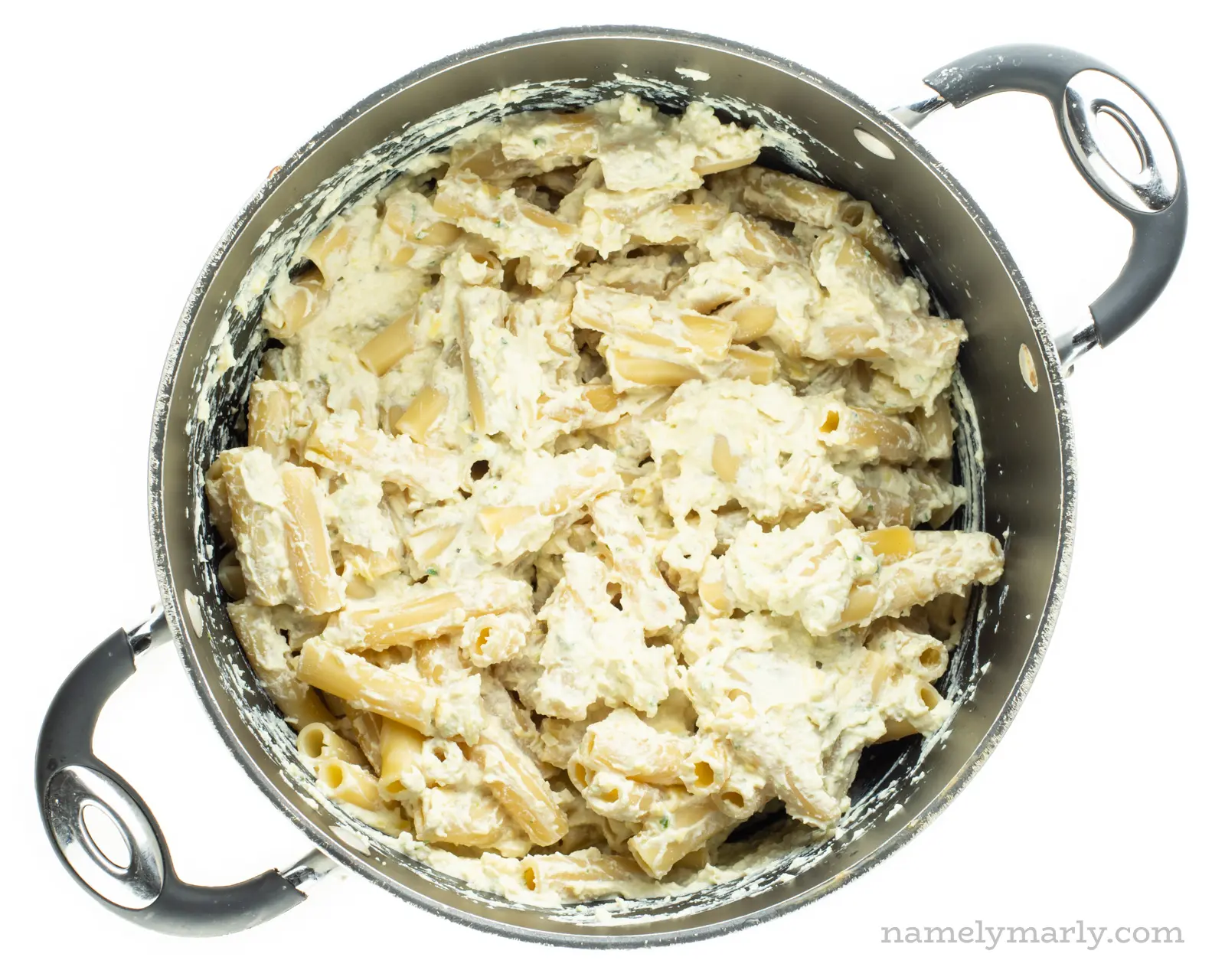 Vegan ricotta has been poured over cooked ziti in a large pot.