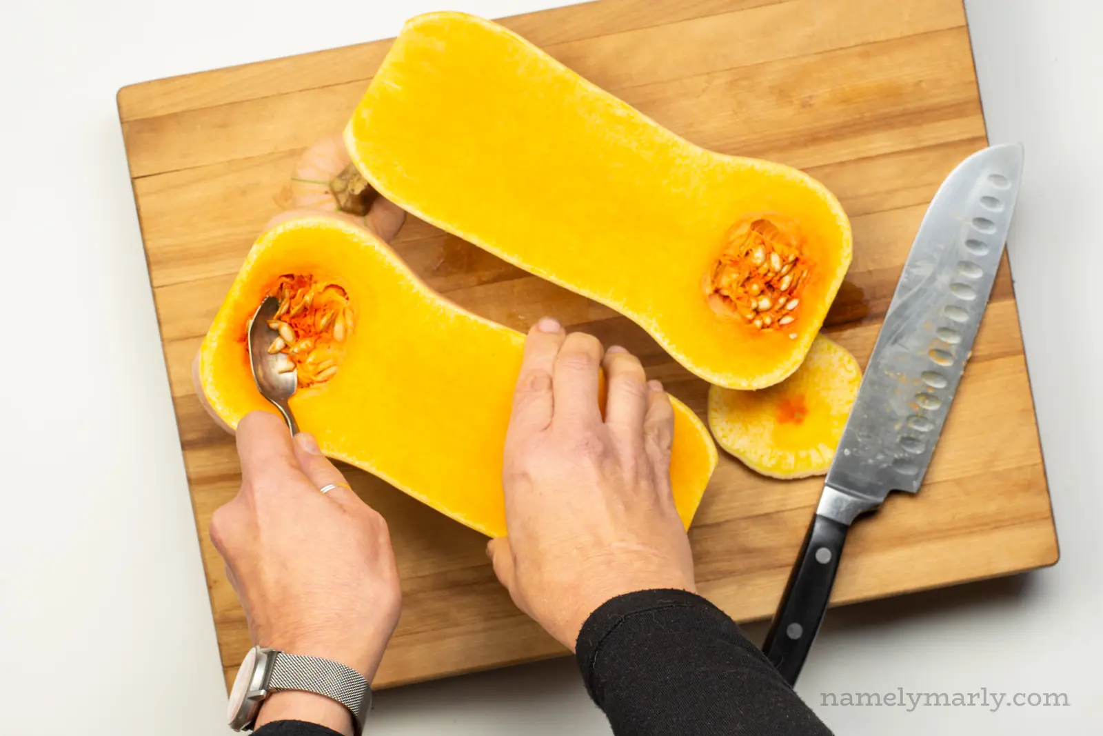 Using a spoon to scoop out seeds from a butternut squash.