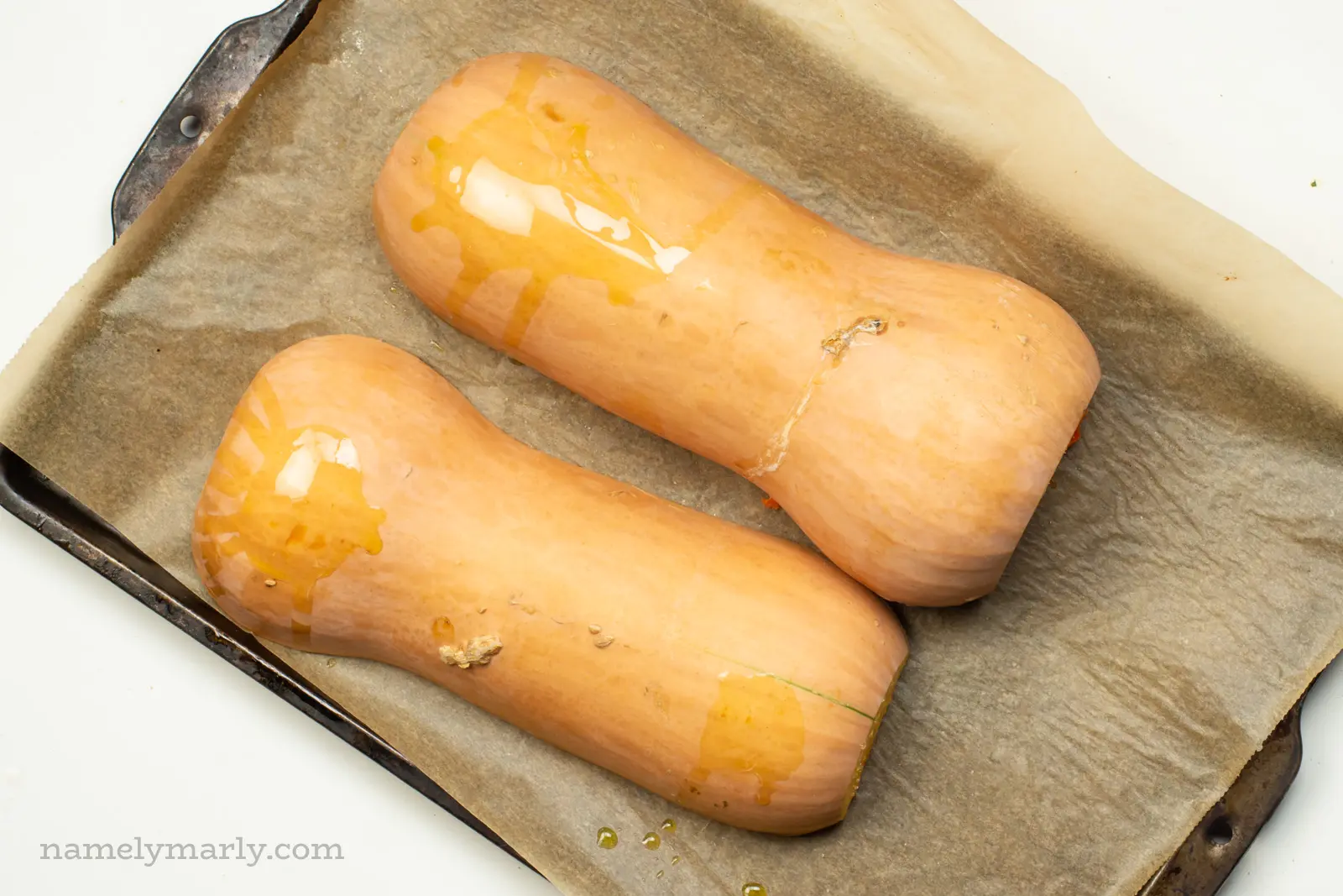 Butternut squash are placed cut side down on a baking sheet.