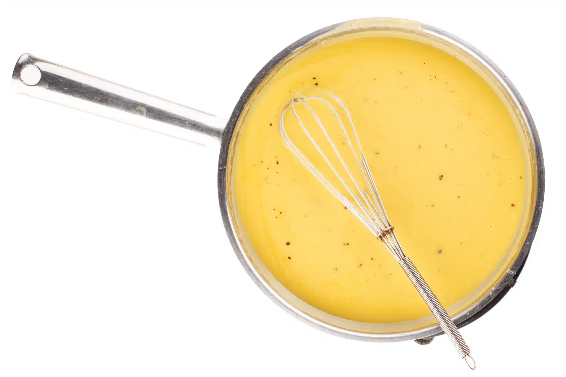 A skillet full of sauce with a whisk in the pan.