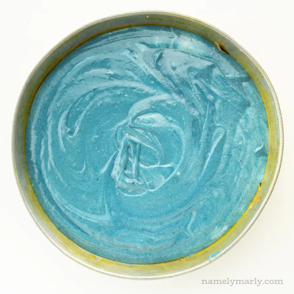 Looking down on blue cake batter in a round cake pan.
