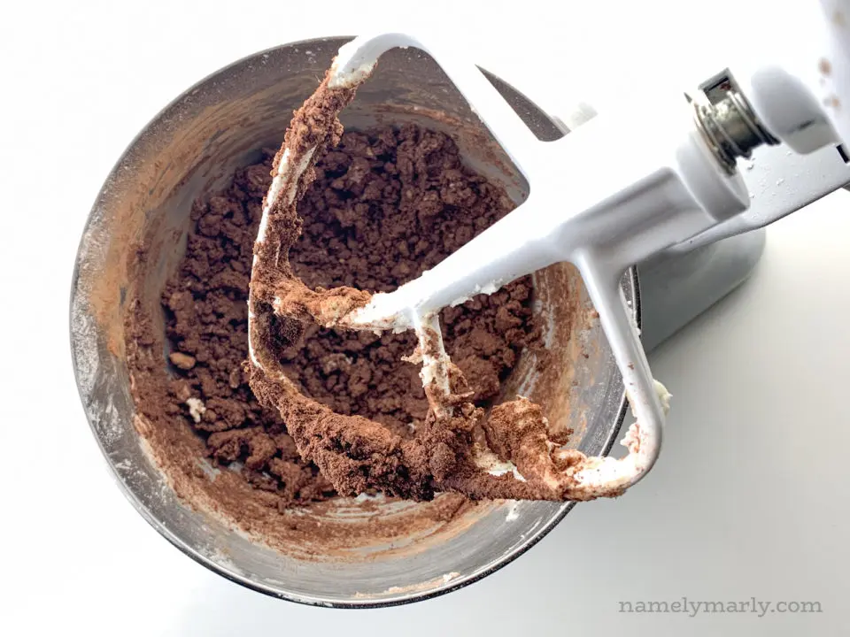Looking down on a stand mixer with cocoa powder added to creamed butter and sugar.
