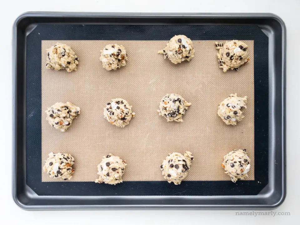 Looking down on a baking sheet with almond joy cookie dough balls ready to be baked.