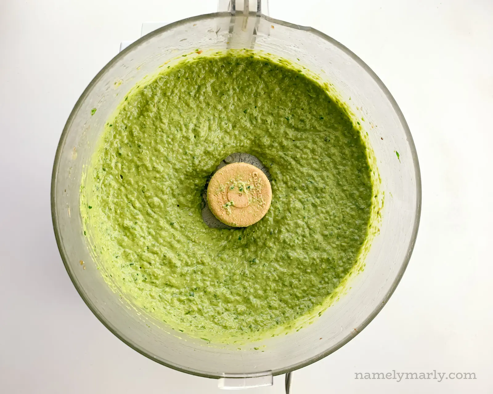 Green hummus in a food processor after being pulsed.