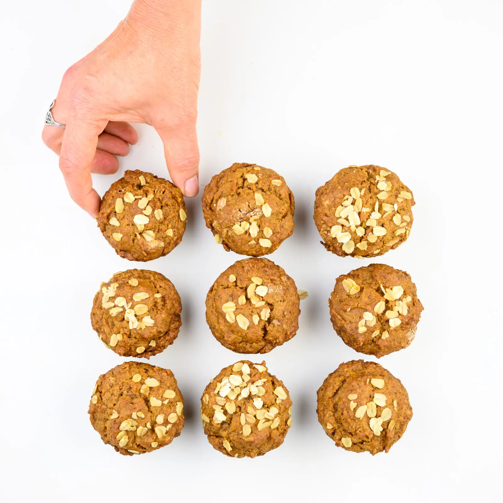A hand reaches into a group of muffins to grab one.