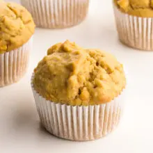 A peanut butter muffin has several muffins around it.