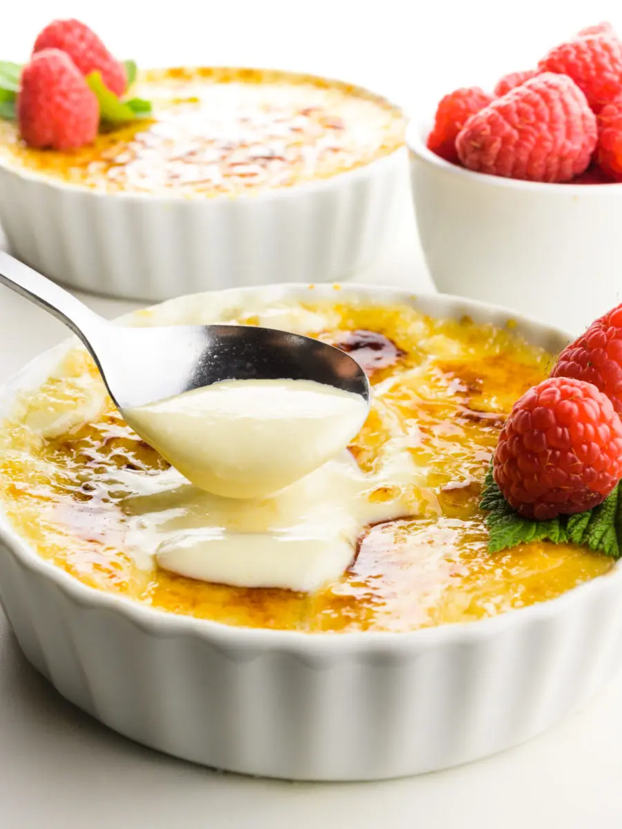 A spoon dishes out some creme from a serving dish of creme brûlée.