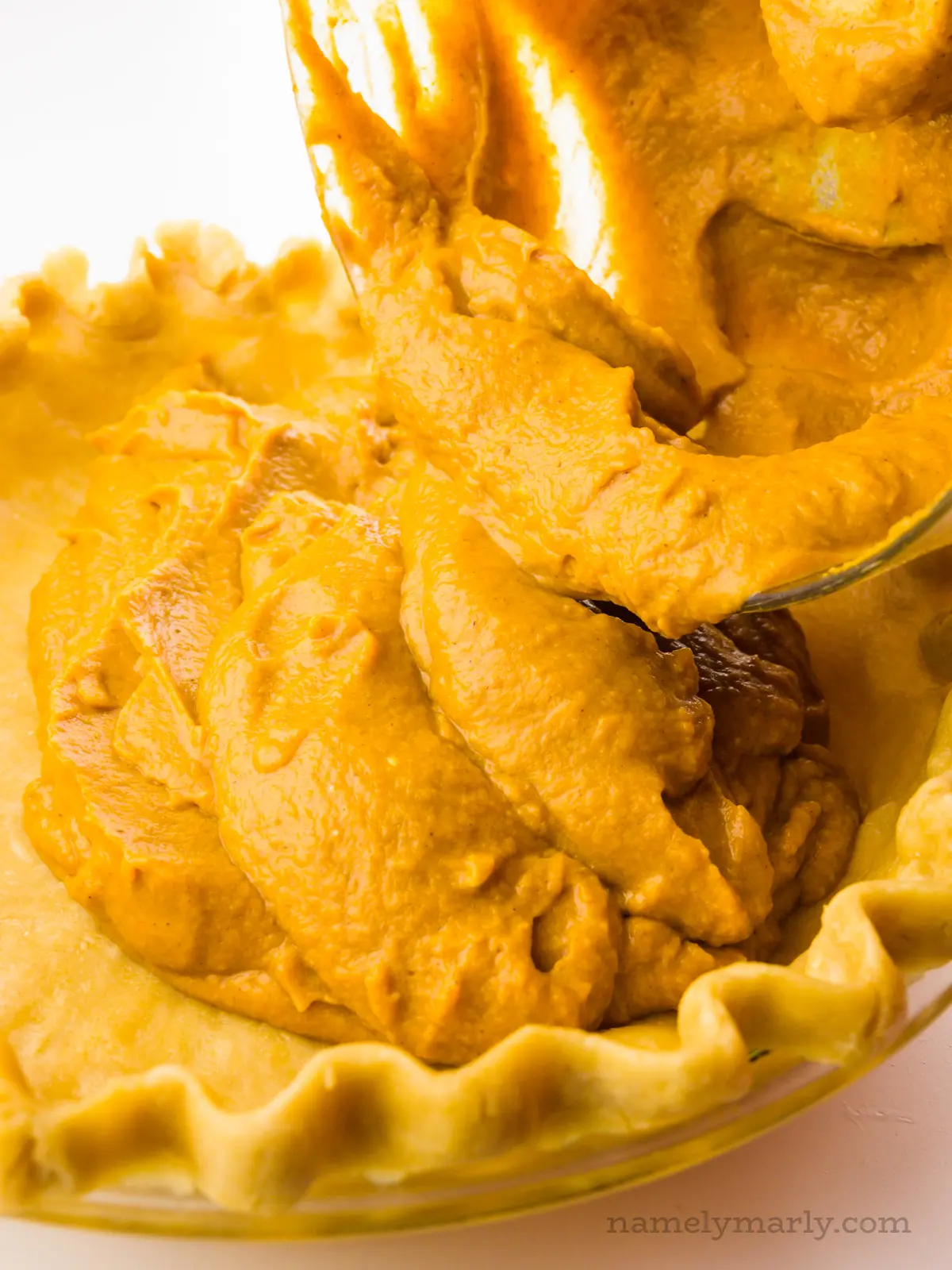 Pumpkin filling is being poured into an unbaked crust.