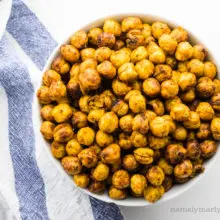 Looking down on a bowl of chickpeas next to a kitchen towel.