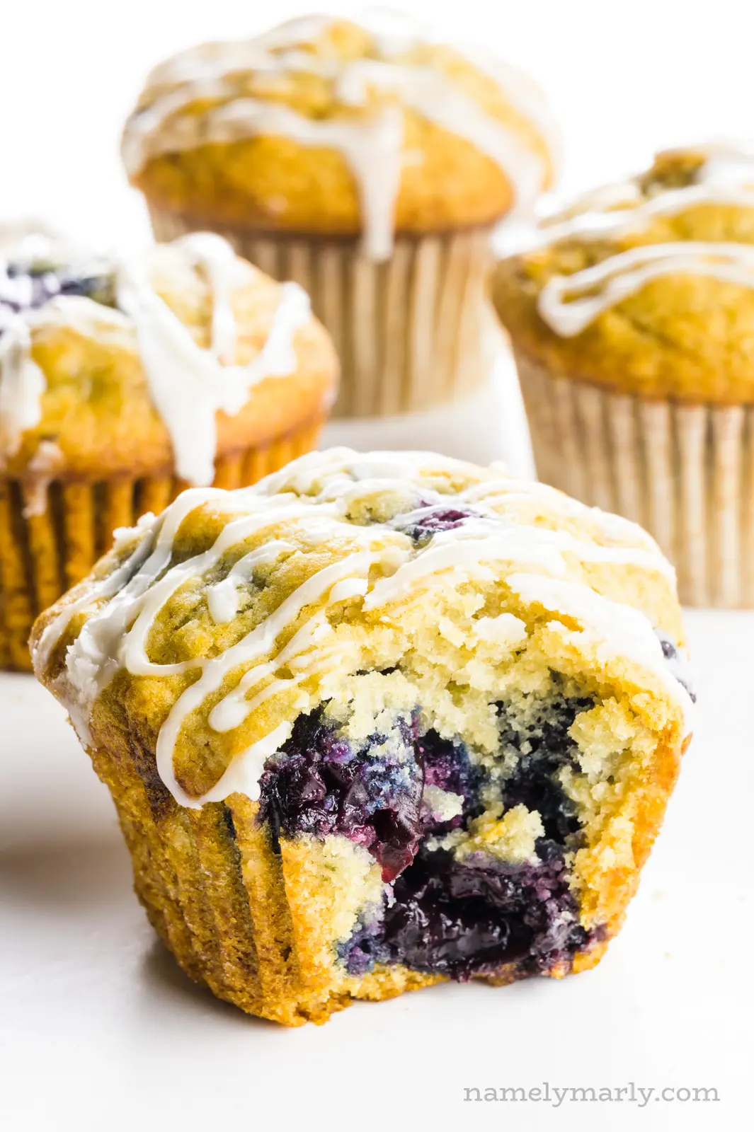 A cherry muffin with a bite taken out of it sits in front of three other muffins.