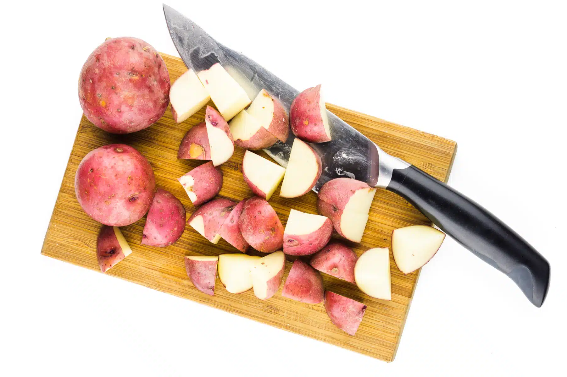 Sliced potatoes sit on a cutting board next to a knife.