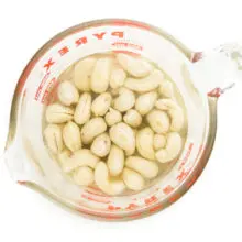 Cashews are soaking in water in a glass pyrex measuring cup.