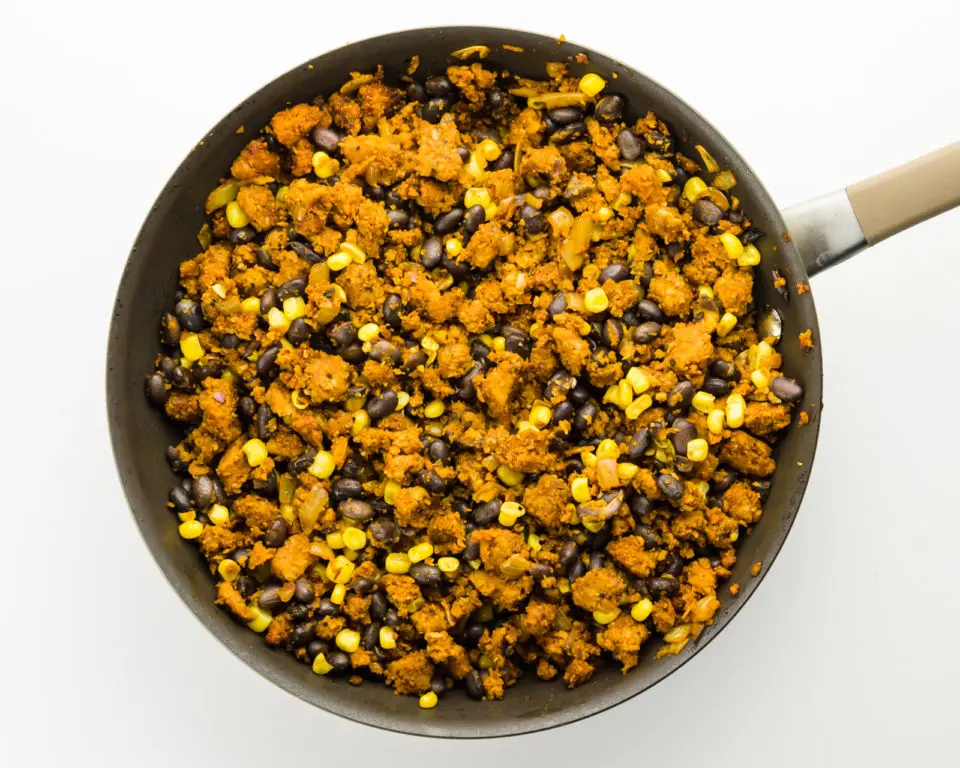 A skillet holds vegan taco meat, combined with black beans and corn.