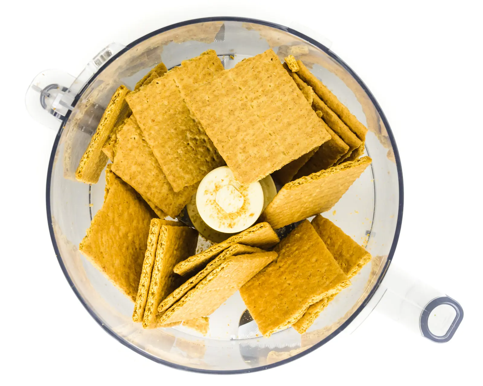 Graham crackers are in the bottom of a food processor bowl.