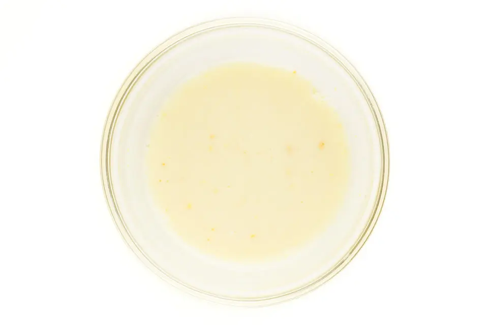A bowl has soy milk inside being curdled with vinegar.