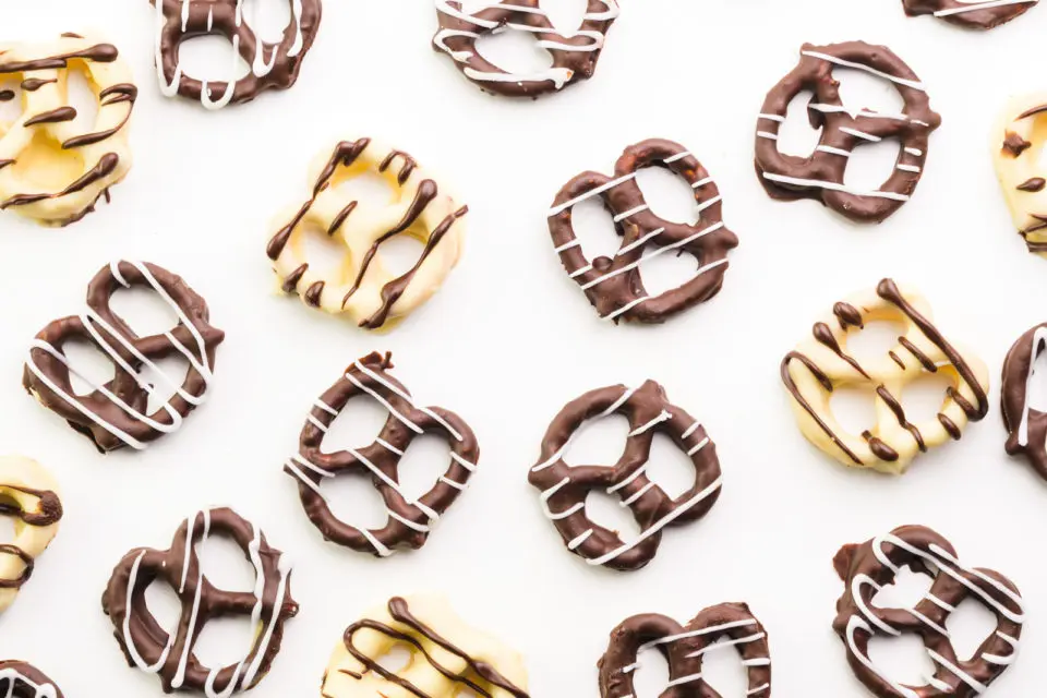 Looking down on a white counter with white and dark chocolate covered pretzels.