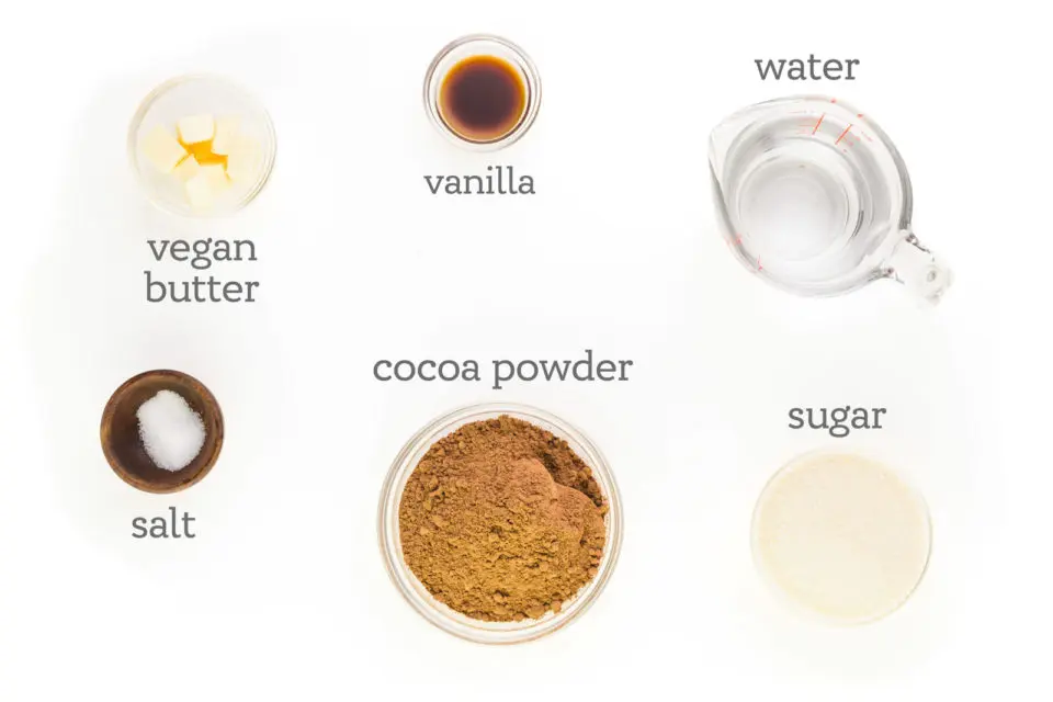 Ingredients are on a white counter. the labels read, "vanilla, water, sugar, cocoa powder, salt, and vegan butter."