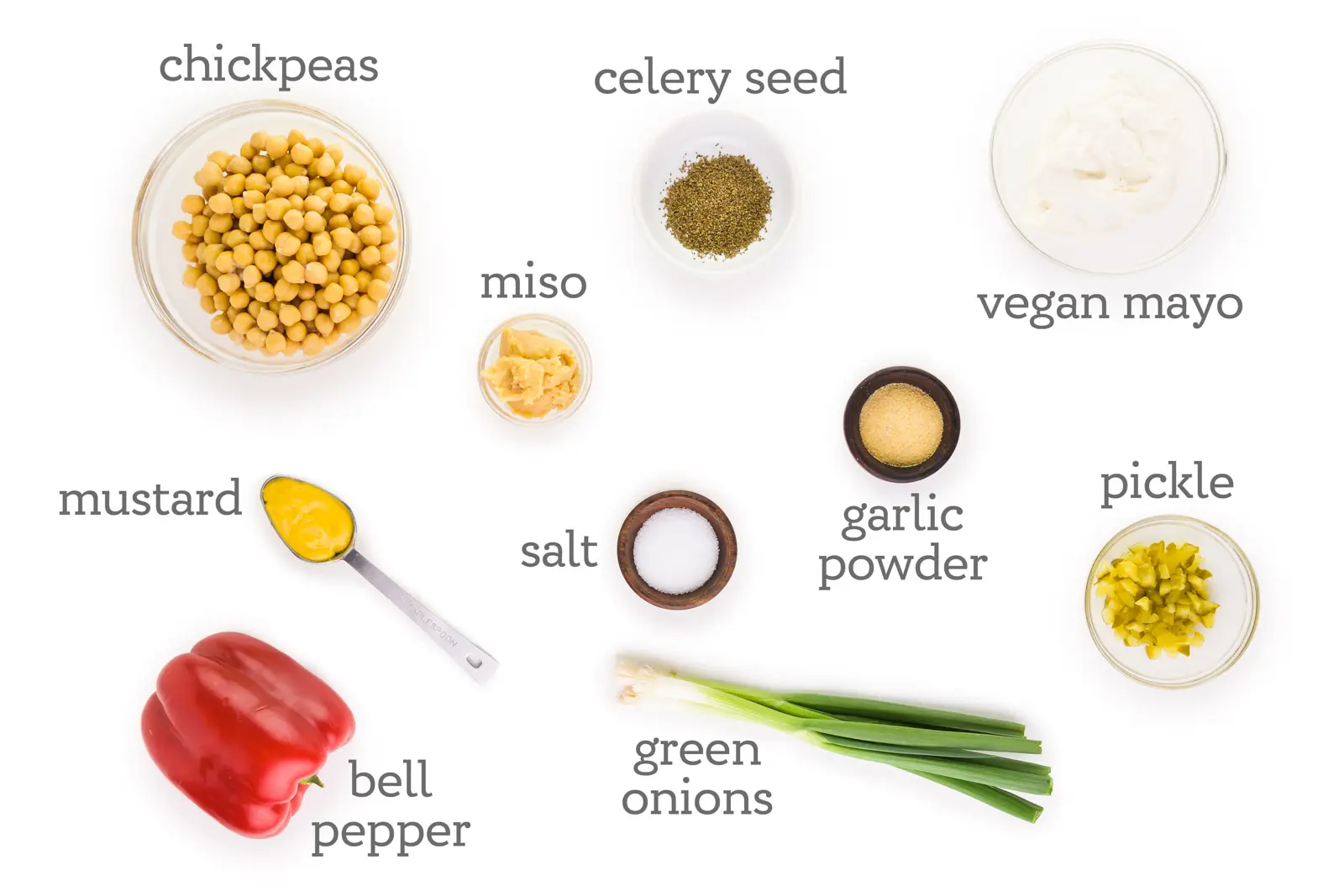 Ingredients are displayed on a white background. The labels read, "chickpeas, miso, celery seed, vegan mayo, garlic powder, pickles, green onions, salt, mustard, and bell pepper."