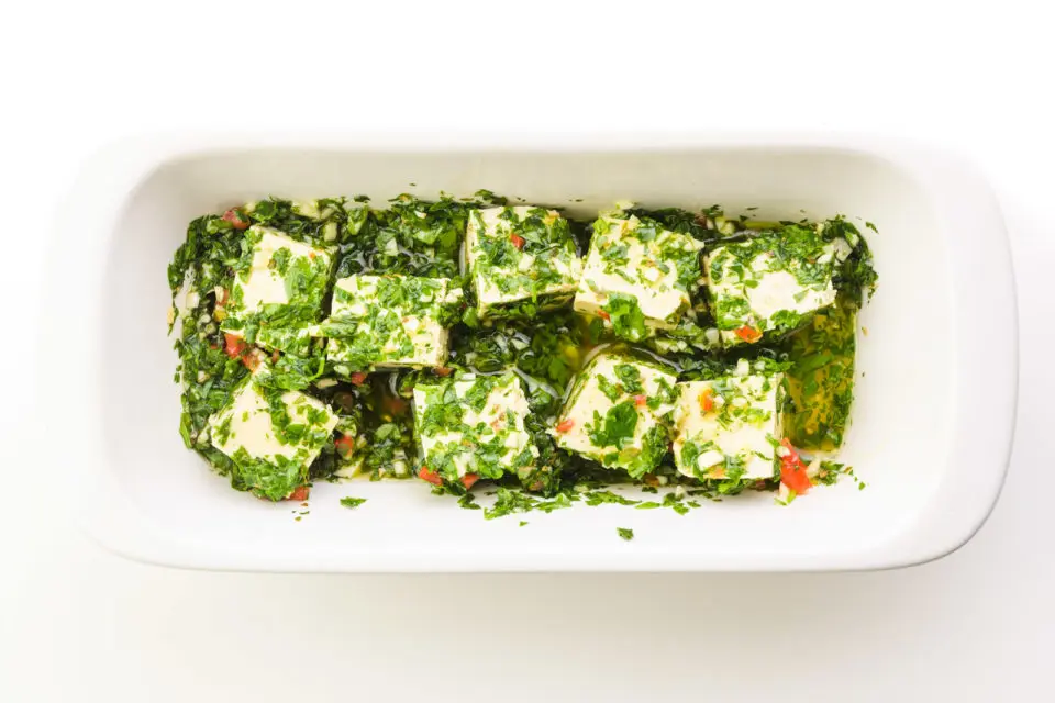 Tofu is marinating in chimichurri sauce before being grilled.