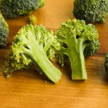 Broccoli has been cut into florets and one of the larger florets has been cut in half.