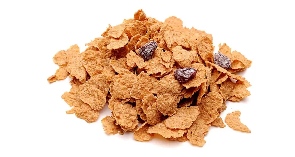 A mound of raisin bran flakes cereal sits on a white counter.
