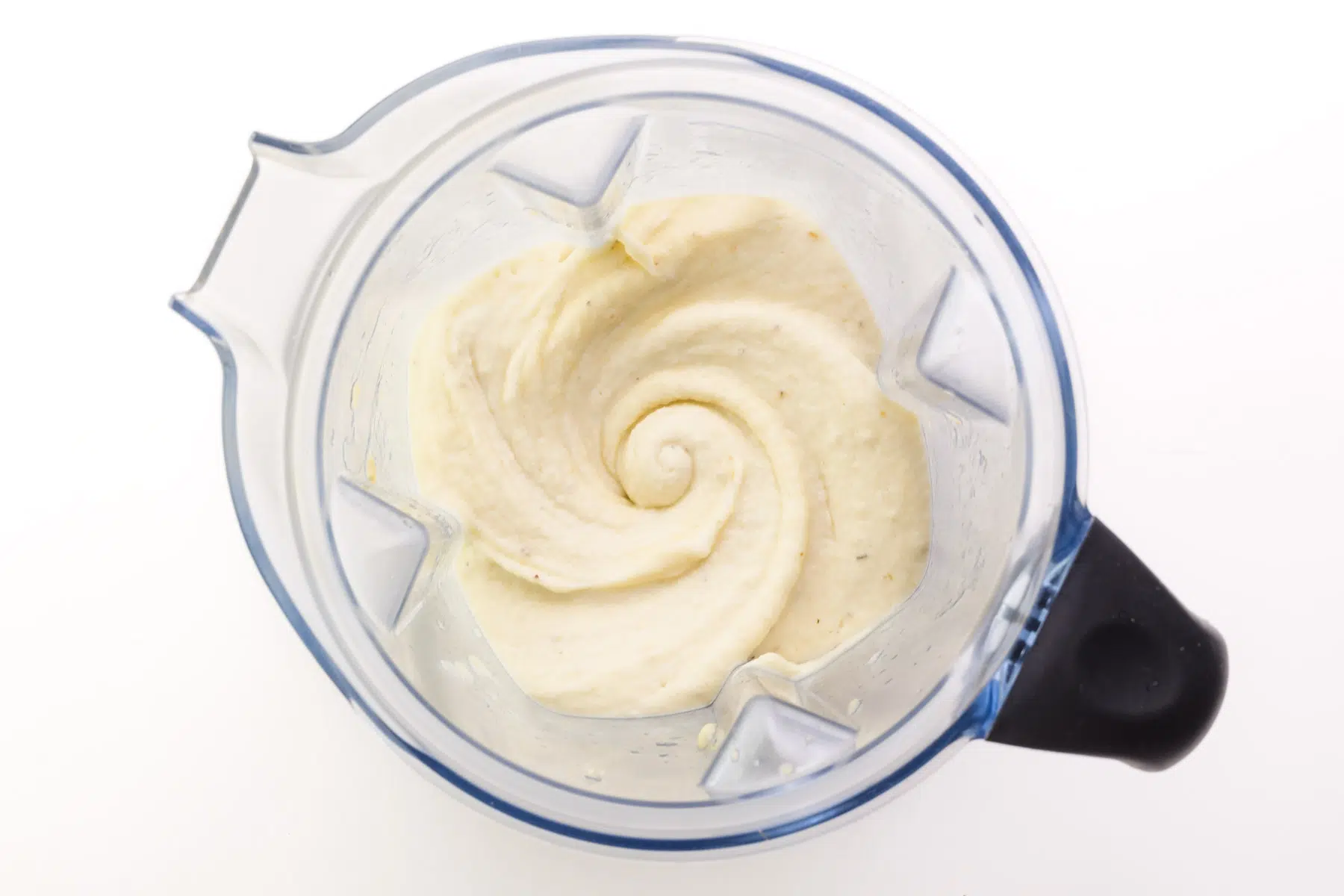 A creamy frozen banana mixture is in the bottom of a blender.