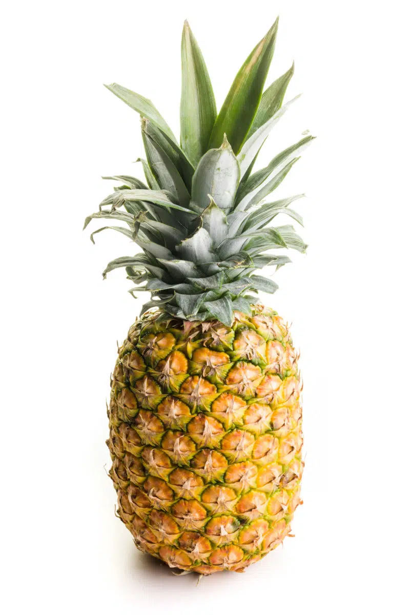 A whole pineapple sits on a white counter.