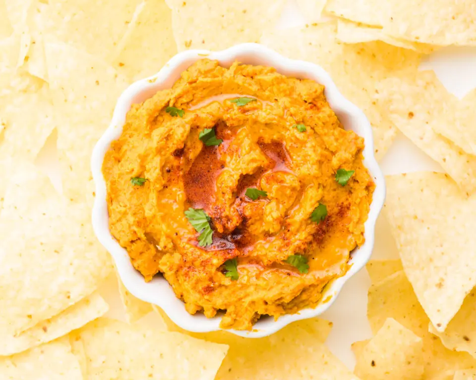 Looking down on a bowl of sweet potato dip surrounded by tortilla chips.