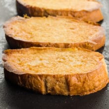Slices of vegan French toast are cooking on a heated griddle.