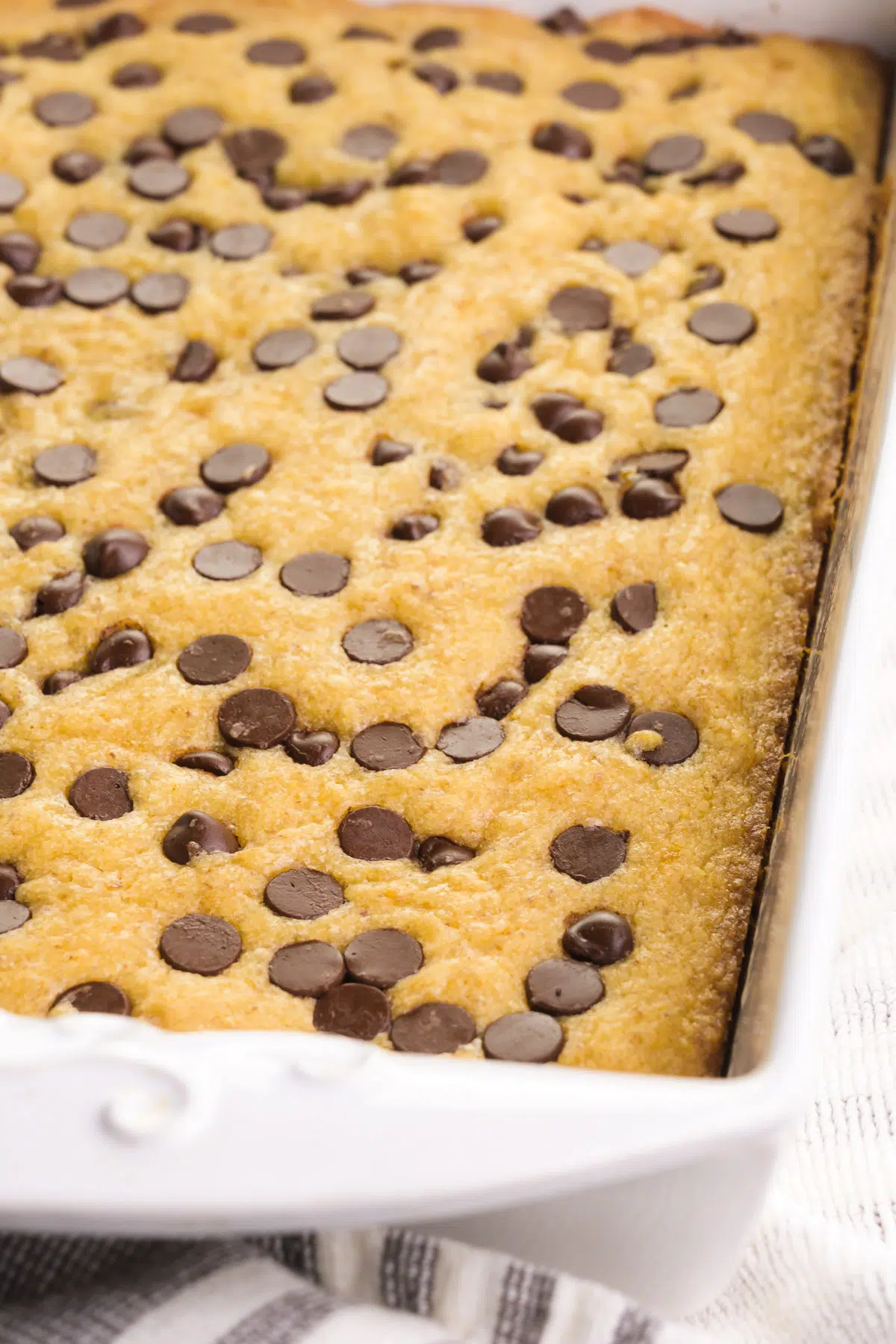 Looking across a pan of blondies with chocolate chips on top.