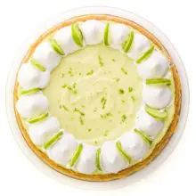 Looking down on a vegan key lime pie with whipped cream on top and lime slices.