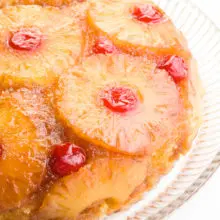 Looking down on a cake with pineapples and maraschino cherries on the outside.