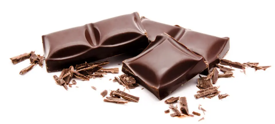 pieces of chocolate bars surrounded by chocolate shavings on a white surface