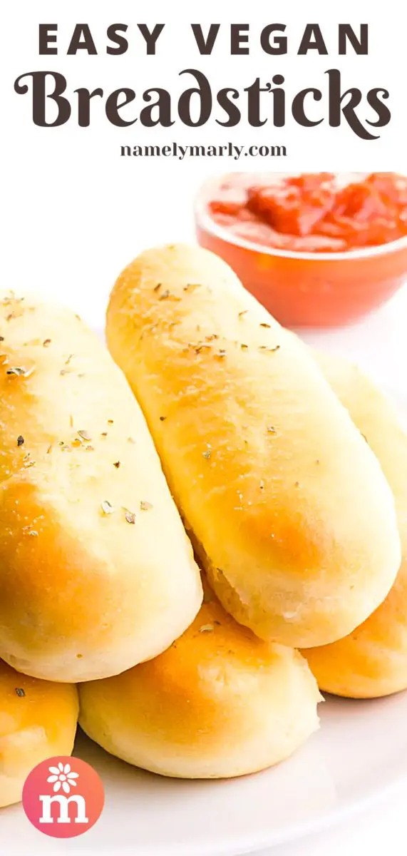 Several breadsticks are on a plate. There is a bowl of marinara sauce in the background. The text at the top of the image reads, Easy Vegan Breadsticks.