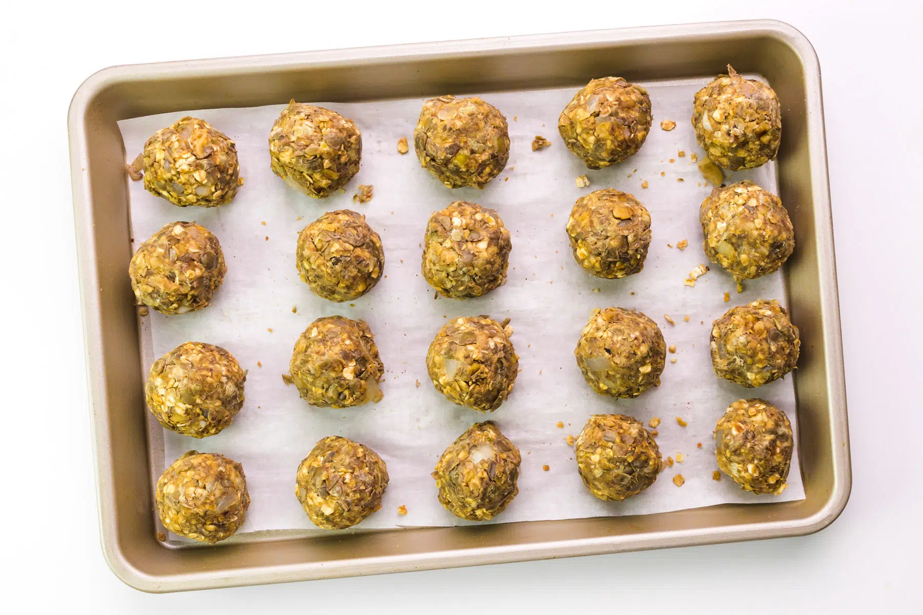 Lentil meatballs are on a baking sheet lined with parchment paper.