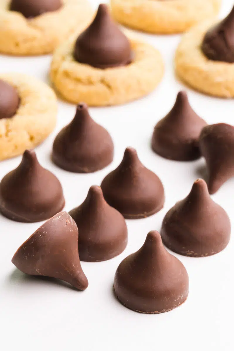 Several dairy-free chocolate kisses sit in front of peanut blossom cookies.