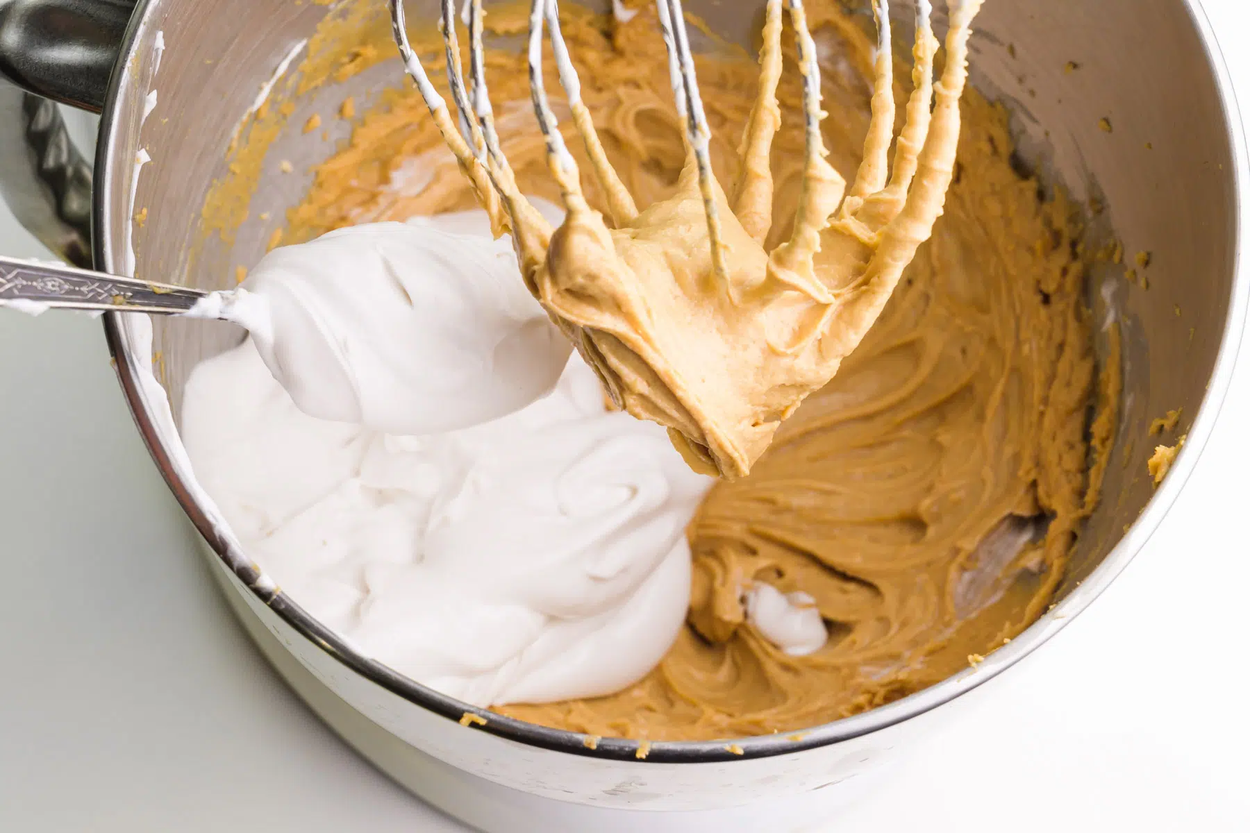 Whipped coconut milk is addied to a stand mixer bowl with a peanut butter mixture.