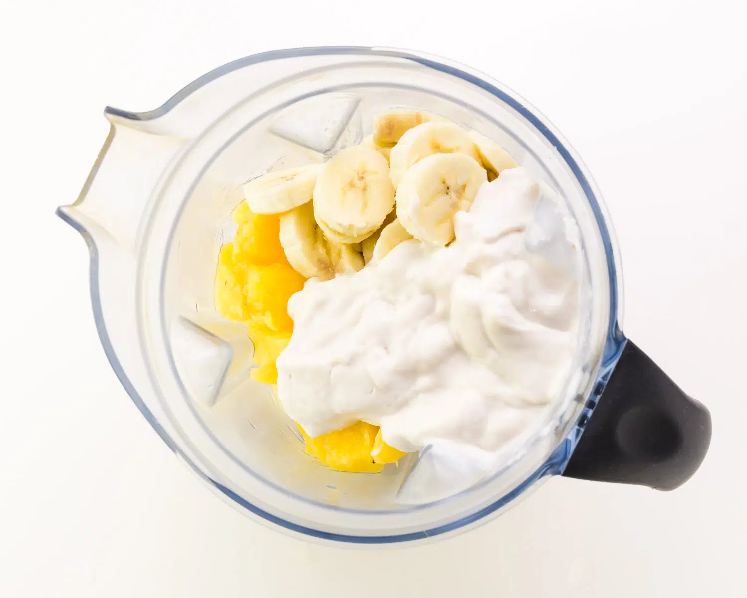 Ingredients are in a blender, including pineapple and bananas.